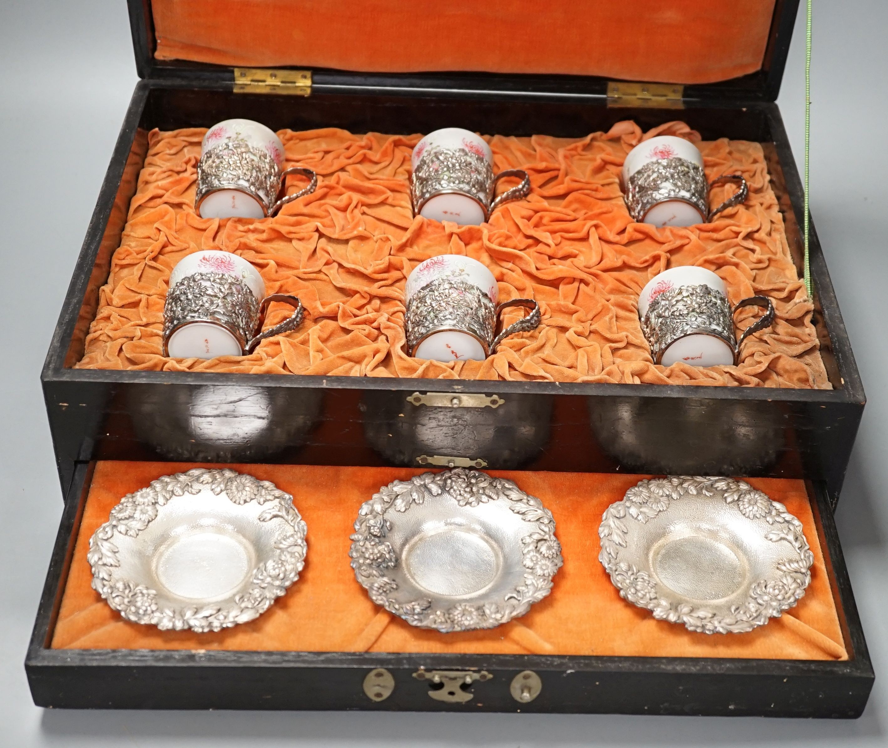 A cased Japanese white metal and eggshell porcelain six piece coffee set, maker’s mark only, case 39.5 cm wide
